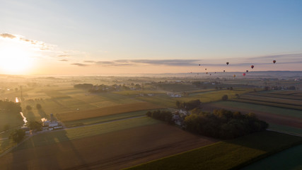 Hot air balloons rise into the air above American countryside in Pennsylvania