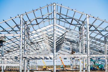 Naklejka premium Steel frame workshop is under construction against a blue sky