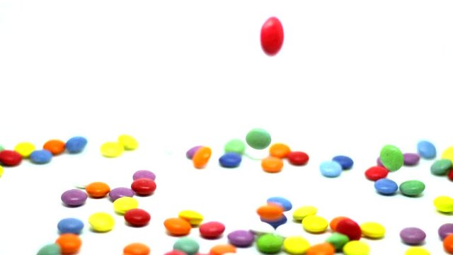 Falling colorful button-shaped chocolates, chocolate dragees, colored pills. White Background