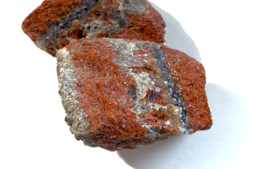 Potassium salt. On a white background lies a sample of cinnamon colored stick mineral with streaks of gray and opal.