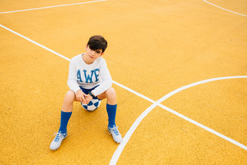 Portrait of soccer player boy sitting on the ball