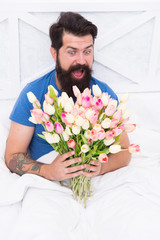 Springtime. good morning flowers. positive mood and happiness. surprised bearded man in bed. birthday gift bouquet. spring fresh tulip. love valentines day. womens day. tulip flower for march 8