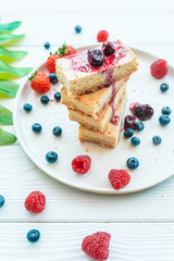 Slice of classic cheesecake with fresh berries on the white plate - healthy organic summer dessert.