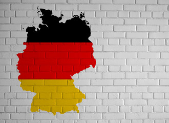 Germany map country silhouette in national German flag colors on white brick wall with copy space for your design.