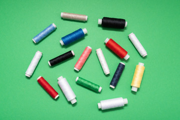 colored sewing threads on green background
