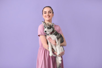 Cute woman with funny husky puppy on color background