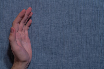 Male hand on blue indigo batiste background texture