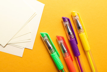 sheet of paper, colored pens, pencils on yellow background