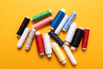 colored sewing threads on yellow background