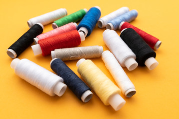 Fototapeta na wymiar colored sewing threads on yellow background