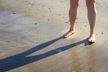 Mature woman's legs below knee on summer beach