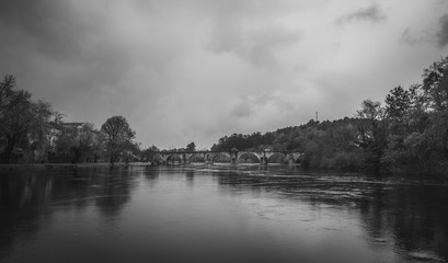 Bonita ponte de pedra antiga sob o rio a preto e branco
