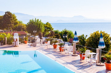 Outdoor pool with vibrant crystal water, parasols and deck chairs located on the coast of Garda...