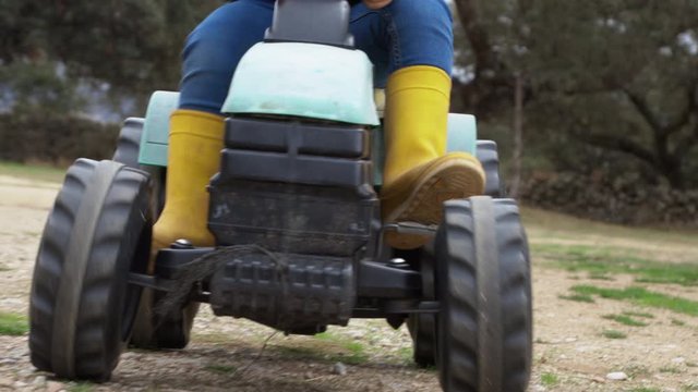 unrecognizable child playing with a toy tractor in the field