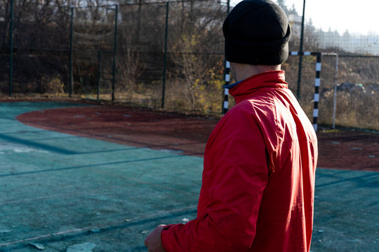 A man in a jacket and hat looks at the football goal
