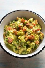 Mexican guacamole with tomato on wooden  background