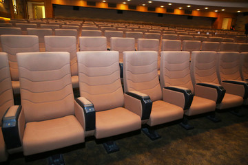 Fototapeta premium wood armed formal plush deep red velvet opera movie theater chairs in curved row with decorative gold molding in fancy carpeted venue