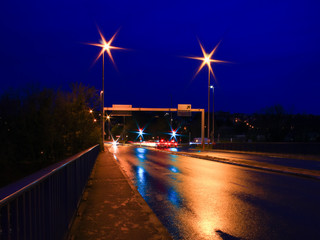 Road sign on the street, empty to place a text. Lightpainting in long exposure mode of a street wet...