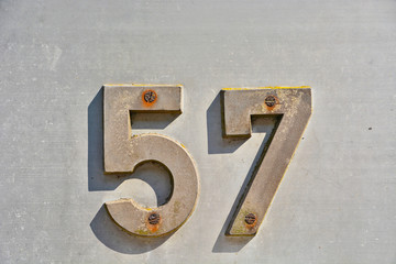 A house number plaque, showing the number fifty seven (57)