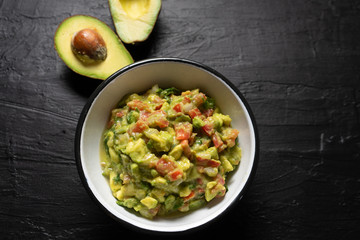 Mexican guacamole with tomato on dark  background