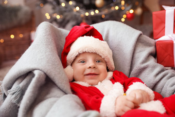 Cute little baby in Santa Claus costume at home