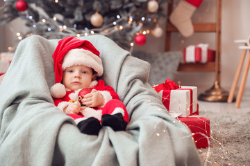 Cute little baby in Santa Claus costume at home