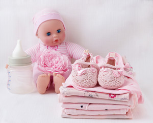 Fototapeta na wymiar Baby clothes for newborn with a doll. In pink colors for girls.