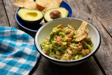 Mexican guacamole with tomato on wooden background
