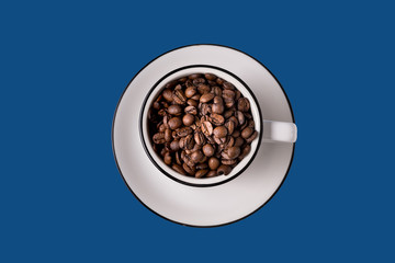 Coffee white cup with coffee beans isolated on classic blue background.