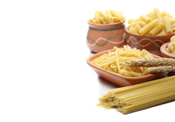 Pasta tubes, dry ears of wheat,   spaghetti, conchiglie grandi, tortiglioni or elicoidali in clay pot, isolated on white background