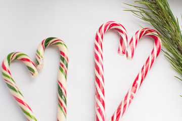 Christmas candy on a white background in the form of hearts, with a spruce branch, there is a free place for writing, top view