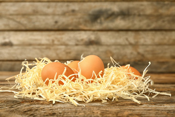 Hay with fresh eggs on wooden background