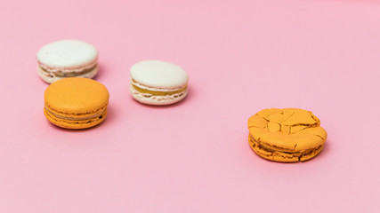 Broken macaroon cake compared to other unbroken on the pink background. The concept of non-ideality, identity; loss and broken soul