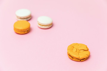 Broken macaroon cake compared to other unbroken on the pink background. The concept of non-ideality, identity; loss and broken soul