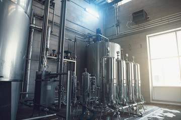 Drinking water factory production, industrial interior. Large metal tanks for filtering and potable...