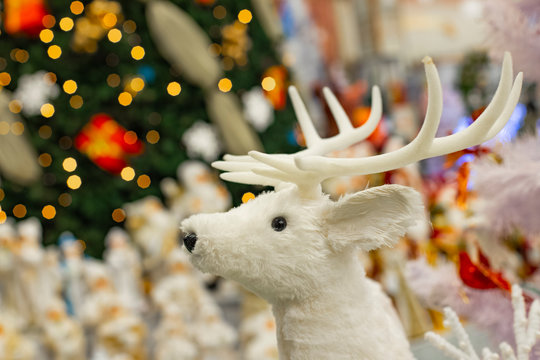 Christmas background picture decorative white deer toy on bright Christmas tree lights winter holidays background