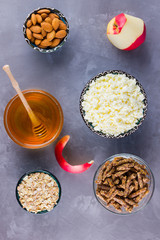 Healthy diet breakfast. Ingredients for a healthy breakfast: oatmeal, granola, honey, almonds, apple, cottage cheese. Homemade granola on a gray background. Top view
