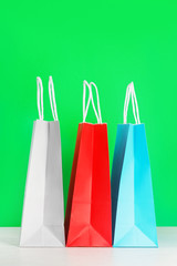 Colorful shopping or gift bags on wooden desk against green background. The concept of shopping or gifts. Layout with a copy space for your ideas.