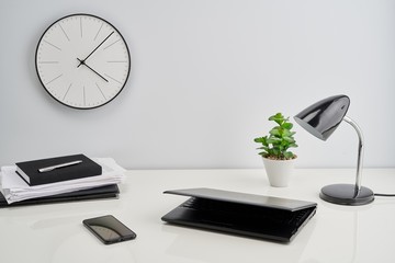 Laptop, lamp and clock on the wall in office