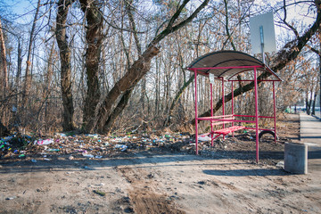 Garbage at the bus stop. People illegally thrown garbage into forest. Concept of man and nature.