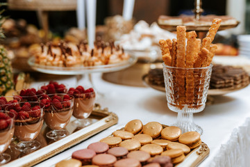 Wedding candybar with desserts, creamy and colorful pastries, delicious cookies, ananas, macarons, muffins