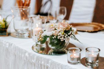 Decoration of a wedding, white flowers, candles and glasses for drinks