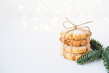 Composition of fresh cookies and fir branch on white wooden table. Close up.