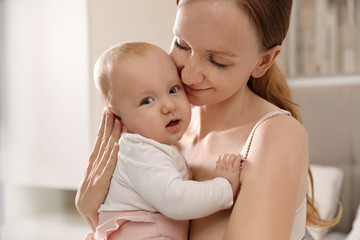 Young woman with her little baby resting after breast feeding in bedroom