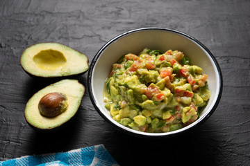 Mexican guacamole with tomato on dark  background