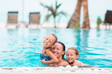 Fototapeta na wymiar Mother and two kids enjoying summer vacation in luxury swimming pool