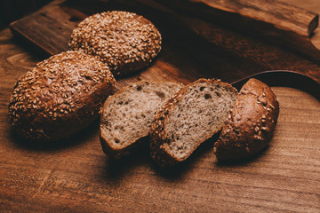 Cereal bread lie on a wooden table with a cutting board.