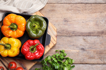 Flat lay composition with tasty stuffed bell peppers on wooden table, space for text