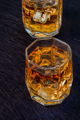 Two glasses of whiskey with ice on a black background - 309851147
