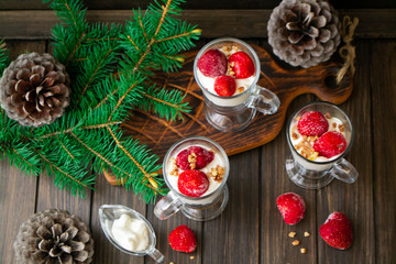 Healthy strawberry parfaits in glass pubs on rustic wooden table decorated by spruce branch and...